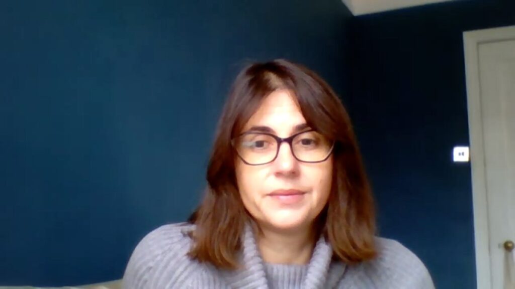 Foto van de auteur met bril en grijze trui voor een donkerblauwe muur